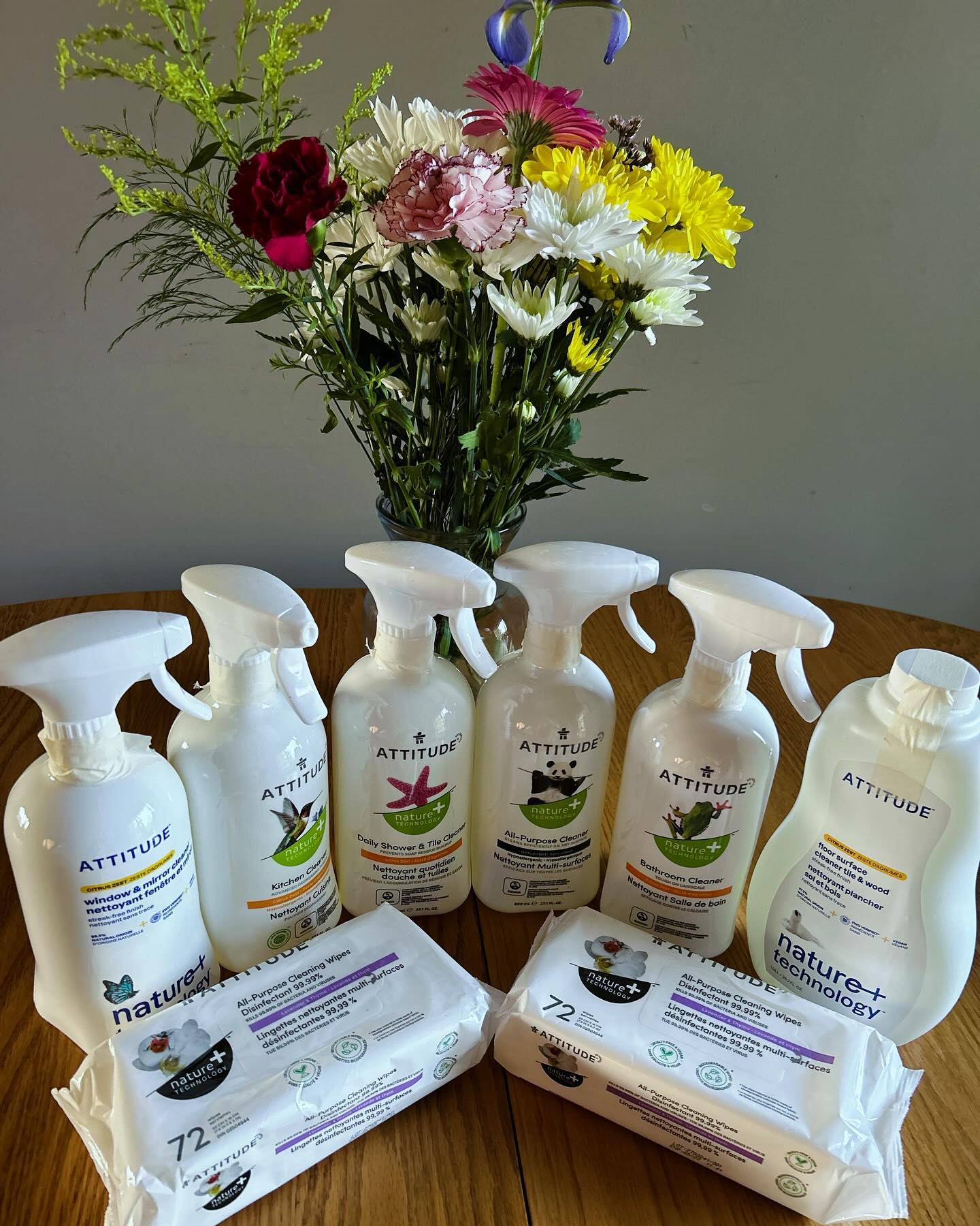 Cleaning products lined up beside a vase of fresh flowers